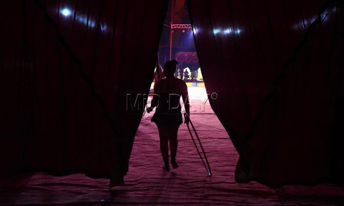 A hula-hoop dancer walks out of the stage area at Rambo circus