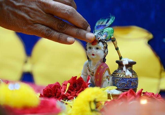 An Indian school teacher marks a statue of Hindu god, Lord Krishna with kumkuma on the occasion of Janamashthami, the birthday of Lord Krishna, in Hyderabad. Pic/AFP