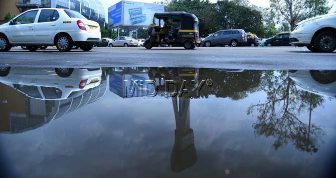 The reflection on the water in a puddle formed on the street near the Chhatrapati Shivaji International Airport in Santacruz shows vehicles passing by. Pic/Rane Ashish