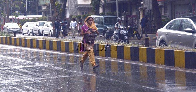 Unprepared for the sudden downpour, a woman runs for cover in Khar. Pic/Pradeep Dhivar