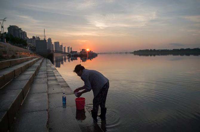 A Chinese woman cleans her clothes near the Friendship bridge on the Yalu River connecting the North Korean town of Sinuiju and Dandong in Chinese border city of Dandong on July 5, 2017.North Korea's test-firing of a missile apparently capable of reaching Alaska underlines the shrinking options for US President Donald Trump to halt Pyongyang's nuclear drive after losing faith in China's mediation efforts.