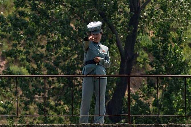 A North Korean soldier gestures as she stands on the banks of the Yalu river near Sinuiju, opposite the Chinese border city of Dandong on July 5, 2017. North Korea's test-firing of a missile apparently capable of reaching Alaska underlines the shrinking options for US President Donald Trump to halt Pyongyang's nuclear drive after losing faith in China's mediation efforts.