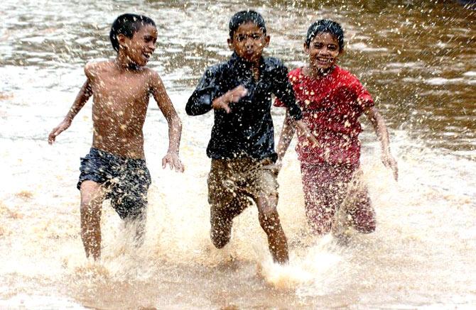 Boys race through a waterlogged street after a downpour in Mumbai, on July 31, 2005