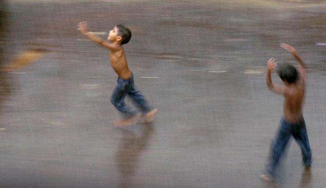 Children enjoy early morning pre-monsoon showers in Mumbai on June 19, 2005