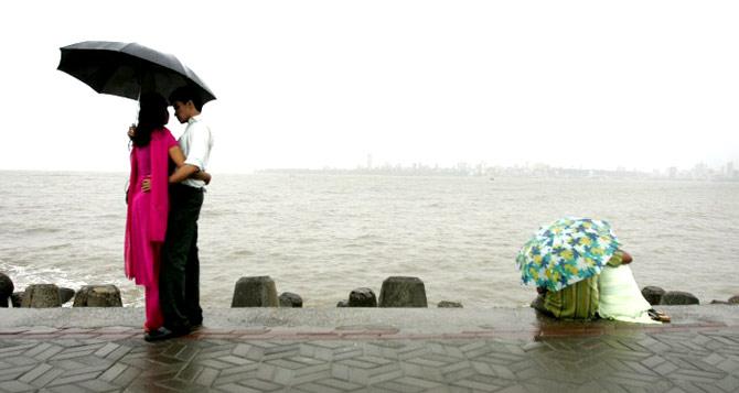 Couples enjoy the view during a rain shower across The Arabian Sea from Mumbai on June 11, 2008