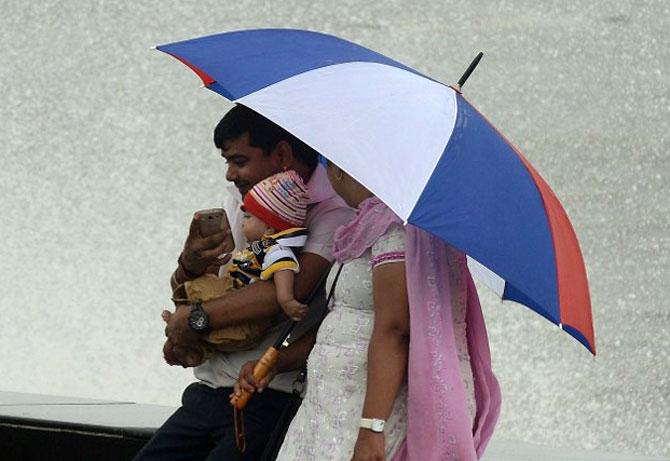 A family sits on the sea front during a light drizzle in Mumbai on June 25, 2013