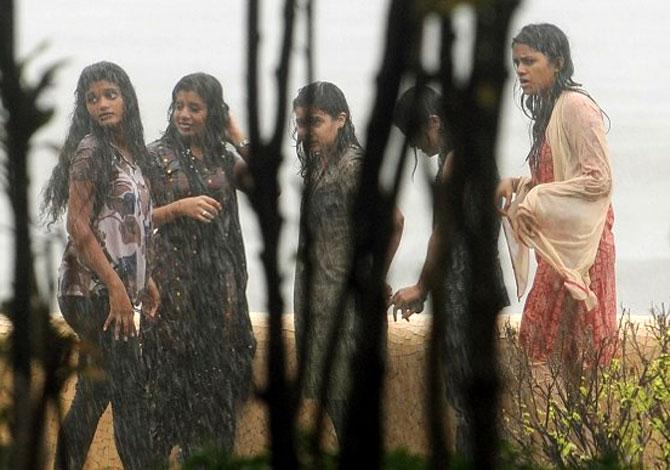 Residents stand in a downpour of heavy rain near the sea front in Mumbai on July 4, 2012