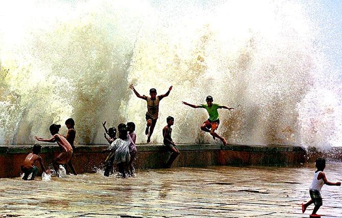 Children have a whale of a time with the huge waves splashing against the coast line of Mumbai, on June 5, 2000