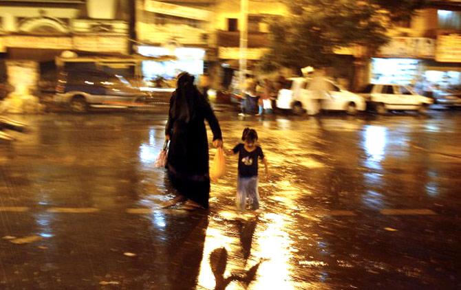A woman and child walk along a street during the first monsoon rain showers in Mumbai on May 31, 2007