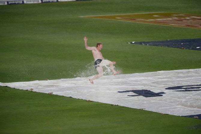 Slider : A streaker dives onto a rain cover on the water logged pitch