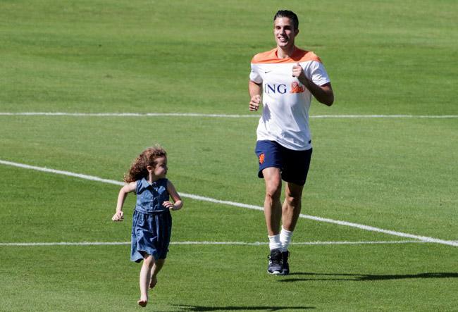 Netherlands' Robin van Persie runs along with his daughter during a training session