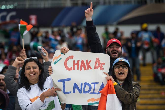 Indian cricket fans cheer and wave national flags during the ICC Champions trophy match between India and Pakistan