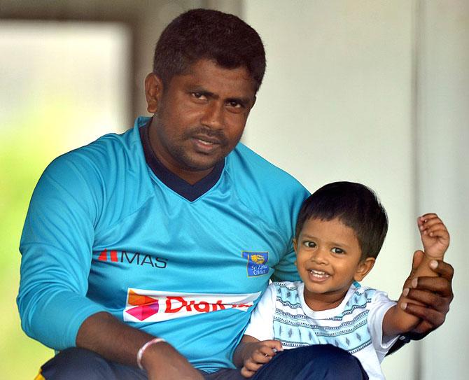 Sri Lankan bowler Rangana Herath (L) with his son during a practice session at Galle. Pic/ AFP