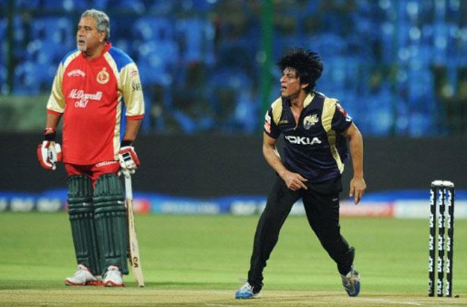 Bollywood actor and co-owner of Kolkata Knight Riders, Shah Rukh Khan (R) bowls as then co-owner of Royal Challengers Bangalore Vijay Mallya (L) looks on during a friendly match between support and administrative staff of Royal Challengers Bangalore and Kolkata Knight Riders IPL teams at The M. Chinnaswamy Stadium in Bangalore on May 14, 2011.