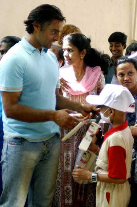 Pakistani pace bowler Shoaib Akhtar (L) distributes gifts to patients at the Cancer Patients Aid Association in Bombay, in April 2004. Shoaib who is in the city for an advertisiment shoot, spent time playing cricket and distributing gifts to the patients at the center.