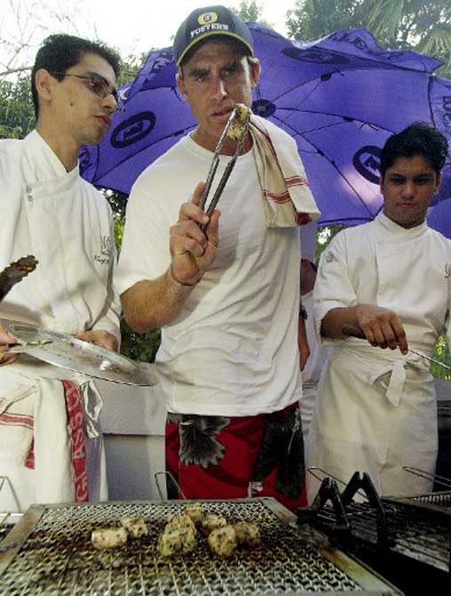 Australian cricketer Matthew Hayden (C) checks with a chef as he grills chicken kebabs at a sponsors party in Bombay in October 2003.