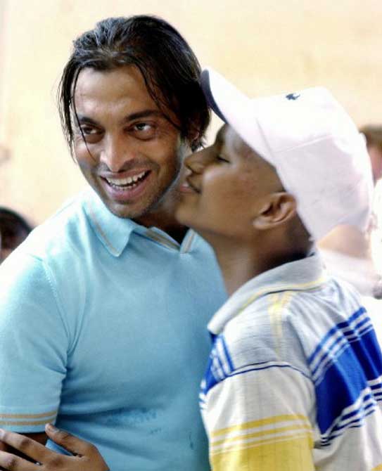 An unidentified Indian cancer patient plants a kiss on the cheek of Pakistani cricketer Shoaib Akhtar (L) at the Cancer Patients Aid Association in Bombay, in April 2004. Shoaib who is in the city for an advertisiment shoot, spent time playing cricket and distributing gifts to the patients at the center.