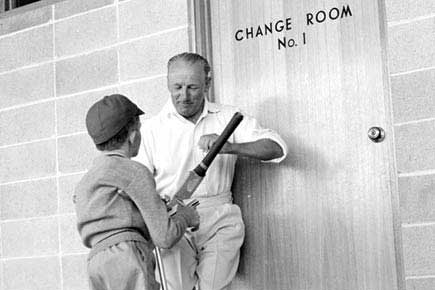 Sir Don Bradman signing an autograph for a young fan