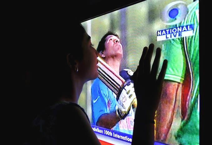 As close as it gets: A young fan of Sachin Tendulkar watches her icon appearing live on a television, in Bangalore on March 16, 2012. The batting superstar, on March 16, became the first cricketer in history to score 100 international centuries, reaching a new record in his glittering two-decade career. Pic/ AFP