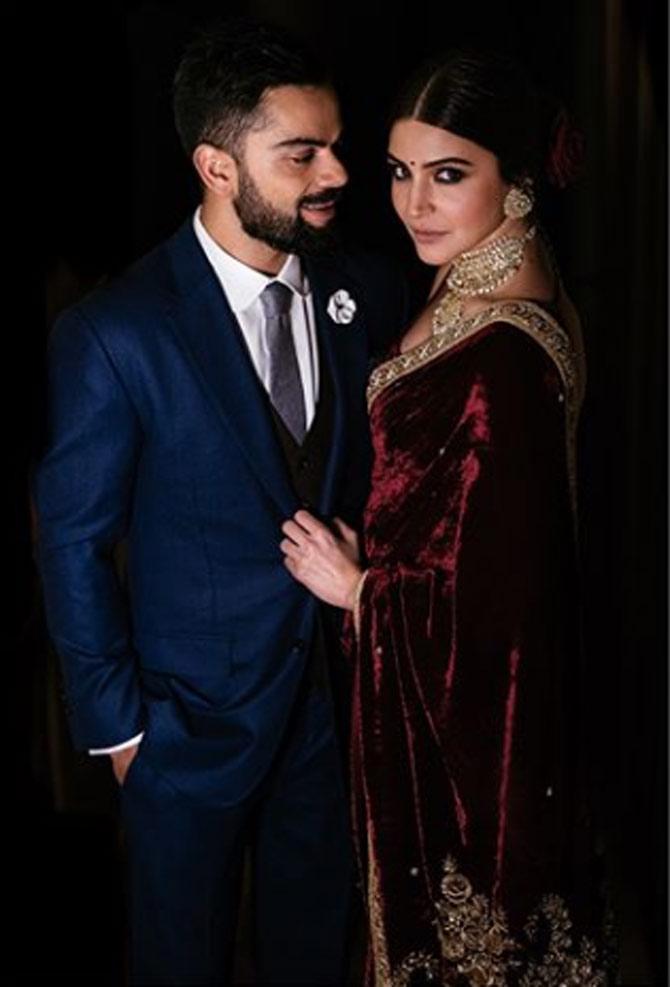 Virat Kohli and Anushka Sharma pose during their engagement ceremony. Virat was looking dapper in a navy blue suit while Anushka looked classy in a wine-coloured saree. (Picture/ Sabyasachi Mukherjee Instagram)